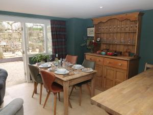 Pudding Hill Barn Cottage في سيرنسيستر: غرفة طعام مع طاولة مع أكواب عليها
