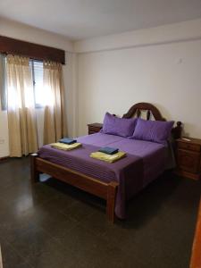 1 dormitorio con 1 cama morada y 2 toallas en Departamentos PLAZA, a 12 metros de la catedral y plaza principal en San Fernando del Valle de Catamarca