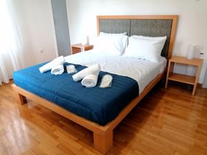 Una cama con manta azul y almohadas blancas. en EstellApartments, en Atenas