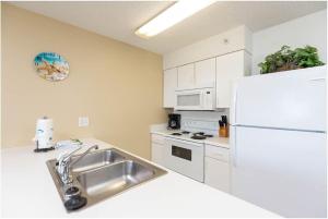 Una cocina con fregadero y refrigerador blanco. en Royal Palms Unit 906, en Gulf Shores