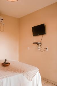 a bedroom with a bed and a tv on the wall at Pousada Aldeia's in Aragarças