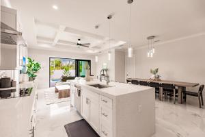 a white kitchen with a sink and a table at Brand New Luxury Naples 4br W Pool By Vanderbilt Beach Coastal Sol By Boutiq in Naples