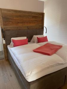 a large bed with two red pillows on it at kleines Seeglück in Feldkirchen in Kärnten