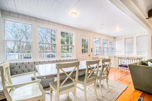 a dining room with a table and chairs and windows at Barefoot Cottage Pool House in Grand Beach