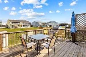 a deck with a table and chairs and an umbrella at Carolina Coasting in Atlantic Beach