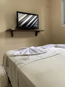 a bedroom with a bed with a tv on the wall at Casa Bouganville in Novo Airão