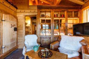 a living room with a couch and a tv and a table at Le Hameau de mon Père in Manigod