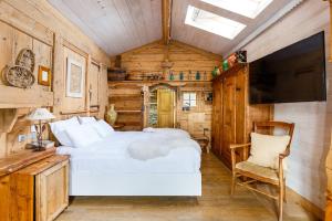 a bedroom with a bed and a flat screen tv at Le Hameau de mon Père in Manigod