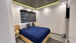 a bedroom with a blue bed and a window at Baja Suites - Departamentos Vacacionales in Ensenada