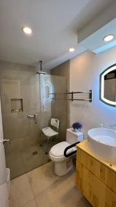 a bathroom with a toilet and a sink and a shower at Baja Suites - Departamentos Vacacionales in Ensenada