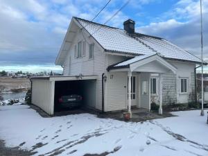 una casa blanca con un garaje en la nieve en Gamle huset på landet en Nøtterøy