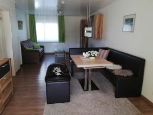 ein Wohnzimmer mit einem schwarzen Sofa und einem Tisch in der Unterkunft Ferienwohnung am Nibelungensteig in Lautertal