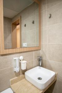 uma casa de banho com um lavatório branco e um espelho. em Sahariano hotel City Center em Laayoune