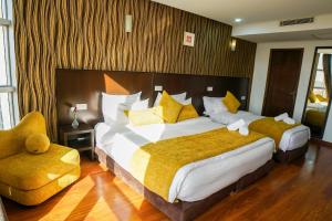 um quarto de hotel com uma cama grande com almofadas amarelas em Sahariano hotel City Center em Laayoune