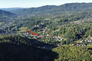 a red airplane flying over a town in a valley at Cottage in traditional village Bradulet, Arges county in Brăduleţ