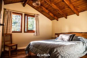 a bedroom with a bed and two windows at Cabaña la vertiente in Lago Puelo