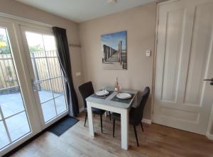 a dining room with a table and chairs and a window at Luxe Kamer aan Zee in Zoutelande