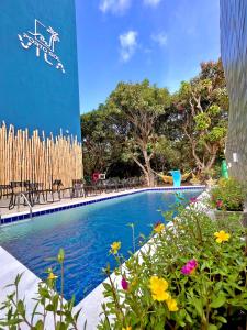 a swimming pool with flowers in front of a building at Porto Vila by AFT in Porto De Galinhas