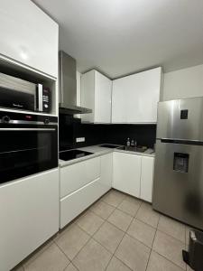 kuchnia z białymi szafkami i lodówką ze stali nierdzewnej w obiekcie Logement La courneuve-Aubervilliers RerB w mieście La Courneuve