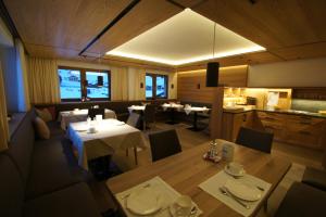 a dining room with tables and chairs and a kitchen at Pension Gallus in Lech am Arlberg