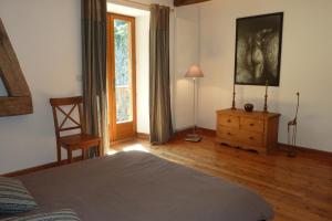 um quarto com uma cama, uma cadeira e uma janela em Le Moulin Ollivier em Saint-André-dʼEmbrun
