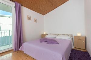 プリモシュテンにあるApartman Burica PRIMOŠTENの紫色のベッドと窓のある寝室