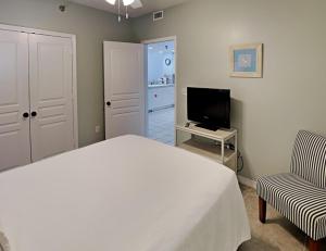Un dormitorio con una cama, un televisor y una silla. en Emerald Isle #302, en Pensacola Beach