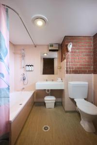 a bathroom with a toilet and a tub and a sink at The Waterloo Hotel in Swansea