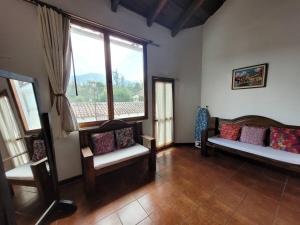 a living room with benches and a large window at Amplia casa Antigua Guatemala con pérgola y jardín in Antigua Guatemala