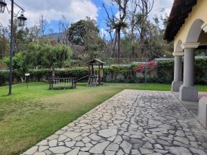 una pasarela de piedra en un patio con parque infantil en Amplia casa Antigua Guatemala con pérgola y jardín, en Antigua Guatemala