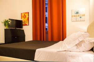 1 dormitorio con 1 cama y una ventana con cortinas de color naranja en La Torre Guest House, en Roma