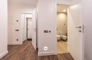 a bathroom with white walls and wooden floors and a toilet at VICTORY-30 LUXURY APARTMENT CEnTER in Kyiv +41 photos