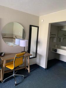 um quarto com uma secretária com um espelho e uma cadeira em Days Inn by Wyndham Louisville Airport Fair and Expo Center em Louisville