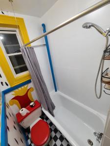 y baño con aseo rojo y ducha. en comfortable private apartment near Manhattan on train, en Woodside