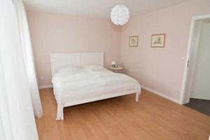 a white bedroom with a white bed and a wooden floor at Ferienwohnung Guddat in Hemsbach
