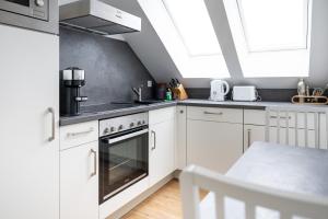 a kitchen with white cabinets and a stove top oven at Ko-Living - urbanes Apartment am Zoo in Giebichenstein +15 photos