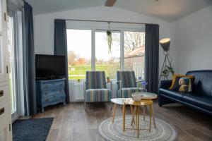 a living room with a couch and a tv and a table at Chalets op Minicamping Dorpszicht in Gapinge