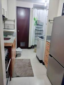 a kitchen with a refrigerator and a brown door at Cubao Manhattanheights U24B TD in Manila