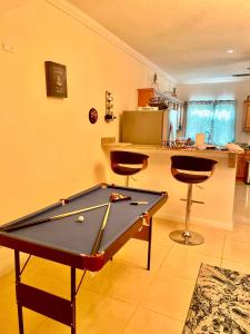 a pool table in a living room with two stools at My Palm Retreat in Mammee Bay