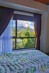 a bedroom with a bed and a large window at Descanso Bajo La Piedra Del Peñol in Guatapé