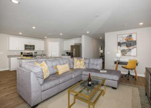 a living room with a gray couch and a kitchen at Grand Getaway House in Foley