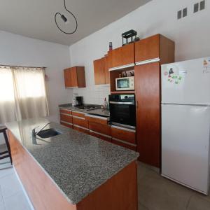 a kitchen with a white refrigerator and wooden cabinets at Los Cardales Mia in Los Cardales