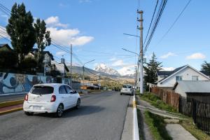 dos autos blancos estacionados en una calle con una montaña en Temporales Ushuaia - Casa Magallanes en Ushuaia