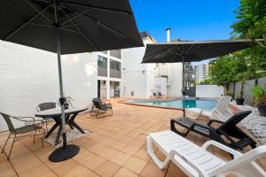 a patio with chairs and tables and umbrellas and a pool at Hamilton Brisbane Airport Hotel in Brisbane