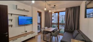 a living room with a couch and a table and a tv at Deluxe Appartement in Cascadas Resort Sunny Beach in Sunny Beach