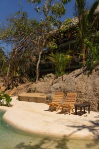 deux chaises assises sur le sable près de l'eau dans l'établissement COCOS HOTEL, à Zipolite