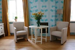 une chambre avec deux chaises et une table avec un vase de fleurs dans l'établissement Haus Keppelborg: ZI Elisabeth mit Burgmauerblick, à Heek