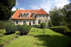 une maison avec un toit orange sur une cour verdoyante dans l'établissement Haus Keppelborg: ZI Elisabeth mit Burgmauerblick, à Heek