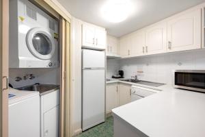 cocina con armarios blancos, lavadora y secadora en Pegasus Motor Inn and Serviced Apartments en Brisbane