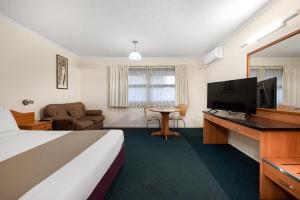 a hotel room with a bed and a flat screen tv at Pegasus Motor Inn and Serviced Apartments in Brisbane